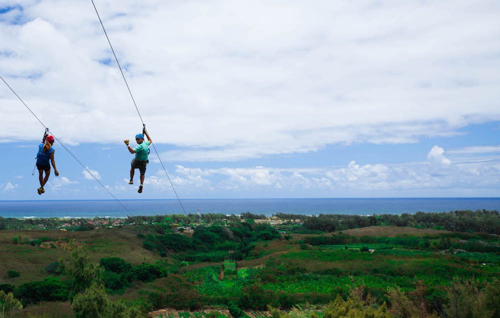 A couple enjoying beautiful views of the ocean while ziplining in Oahu.