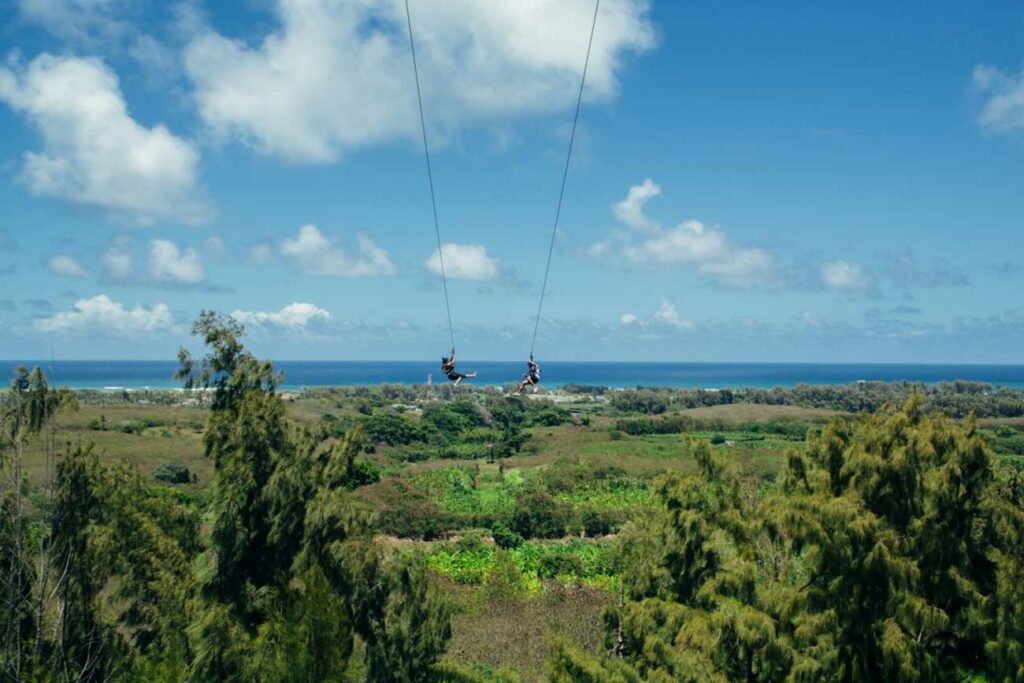 A couple ziplines on dual ziplines facing the North Shore of Hawaii and Keana Farms