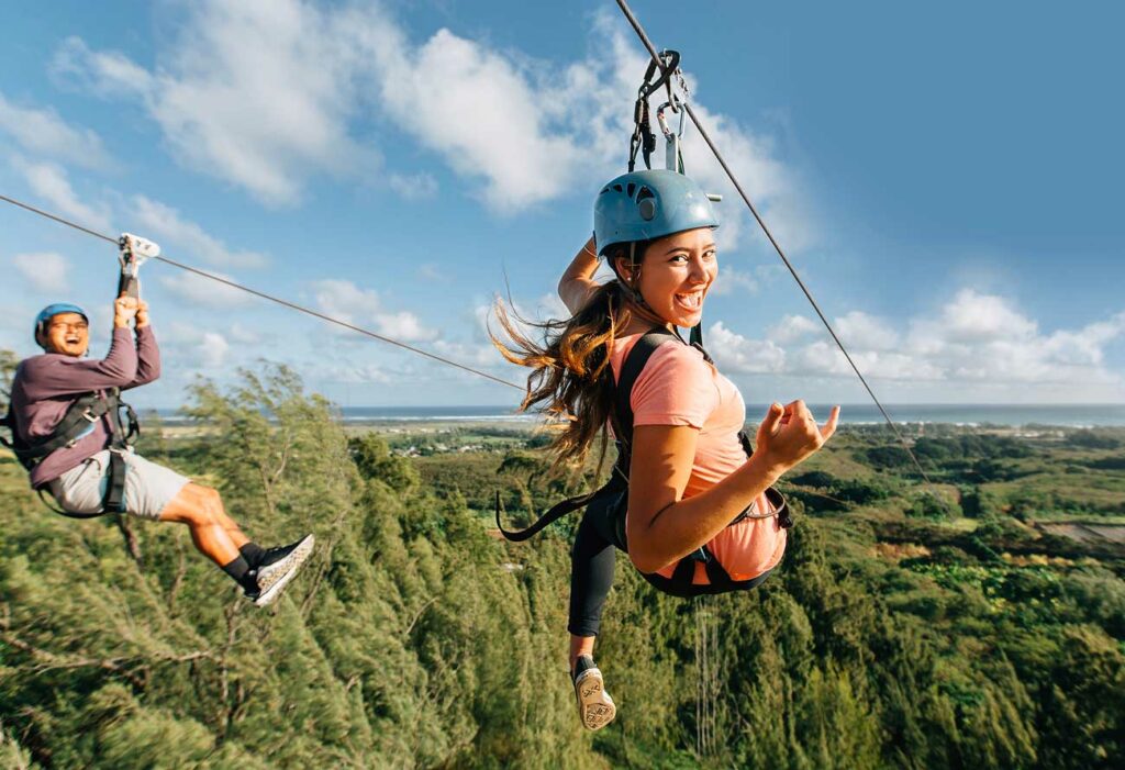A young couple looks back in excitement as they zipline down the longest zipline on Oahu