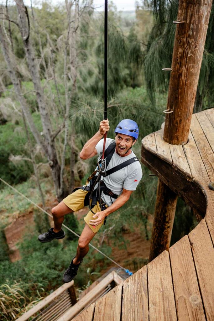 A father smiles in amazement as he rappels off a zipline platform