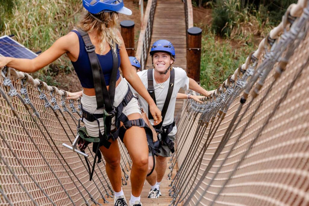 A young man smiles as he follows other climb a floating staircase at CLIMB Works