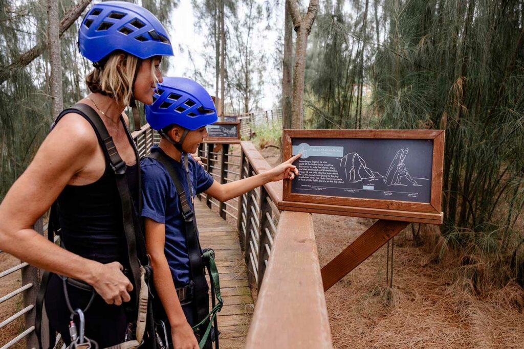 A mother and son learn about Hawaiian culture by reading an informational plaque