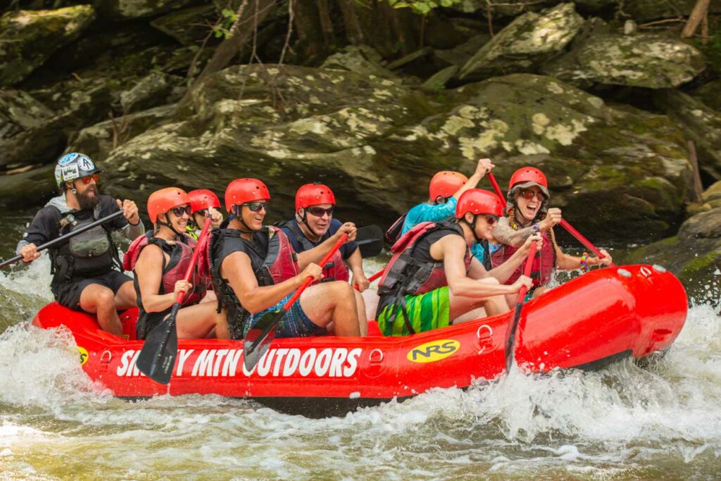 Smiling faces on rafters as they are guided through rapids with Smoky Mountain Outdoors