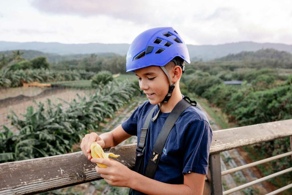 A boy peels an apple banana as he samples the local produce at Keana Farms