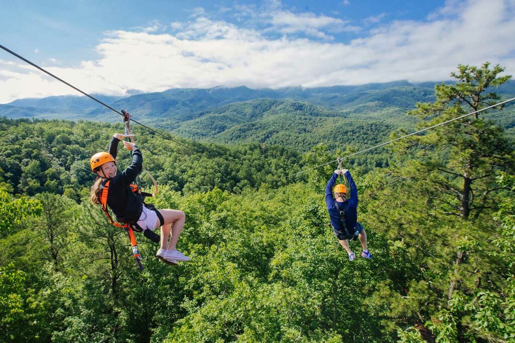 A young girl smiles as she ziplines toward an epic mountain view in the Smokies