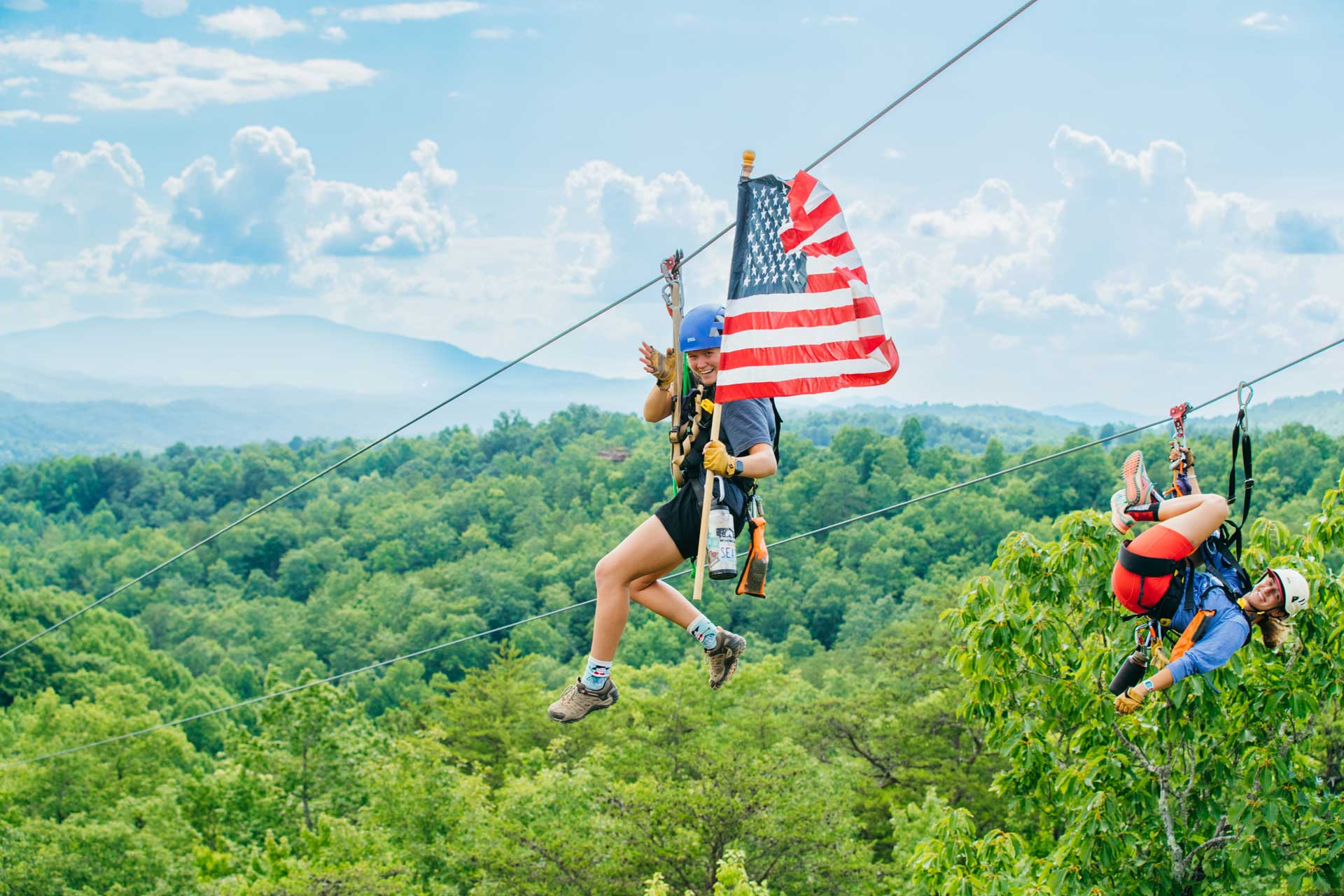 A CLIMB Works Guide zip lining with a flag in Tennessee on the 4th of July