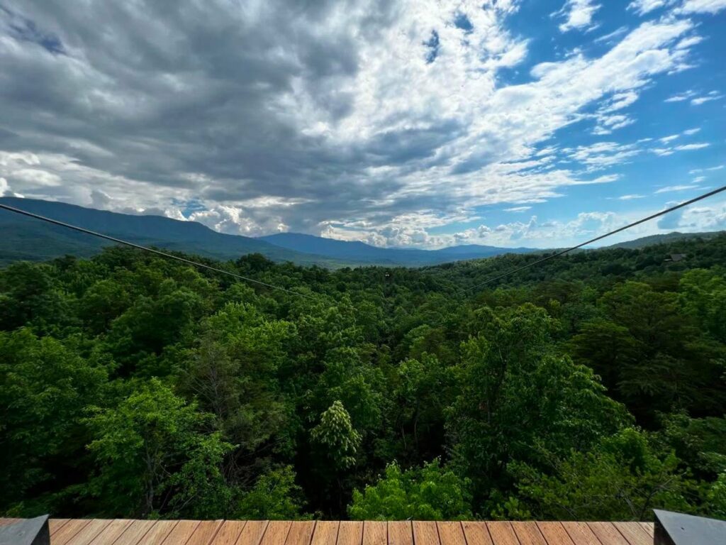 The stunning view from a zipline tower looking down the zipline toward the Great Smoky Mountains