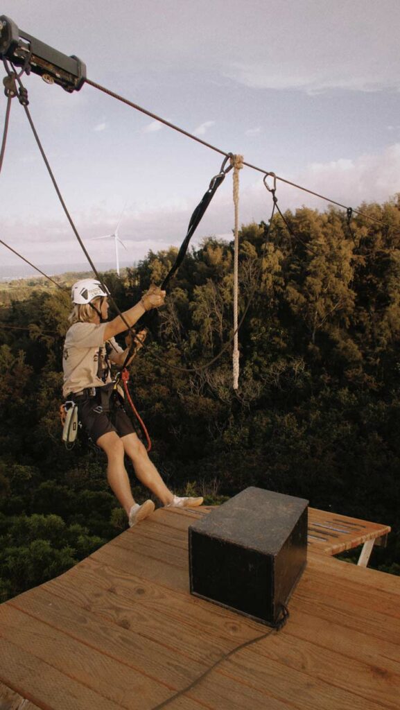 A zipline tour guide secured to the course over looking the mountain landscape in Hawaii