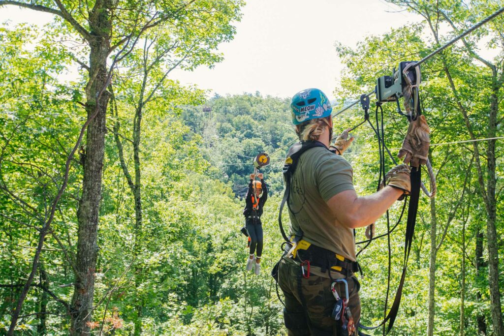 A zipline guide receiving a young smiling girl in Tennessee