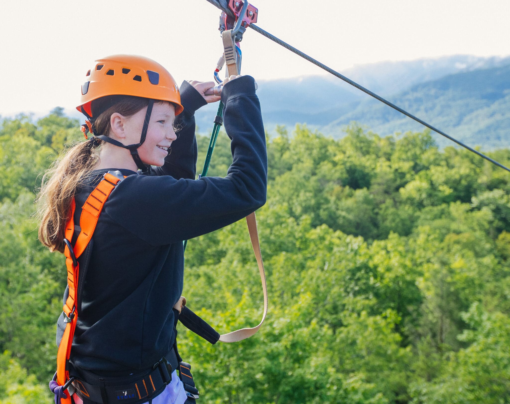 Smiling young girl riding a zipline at CLIMB Works Smoky Mountains